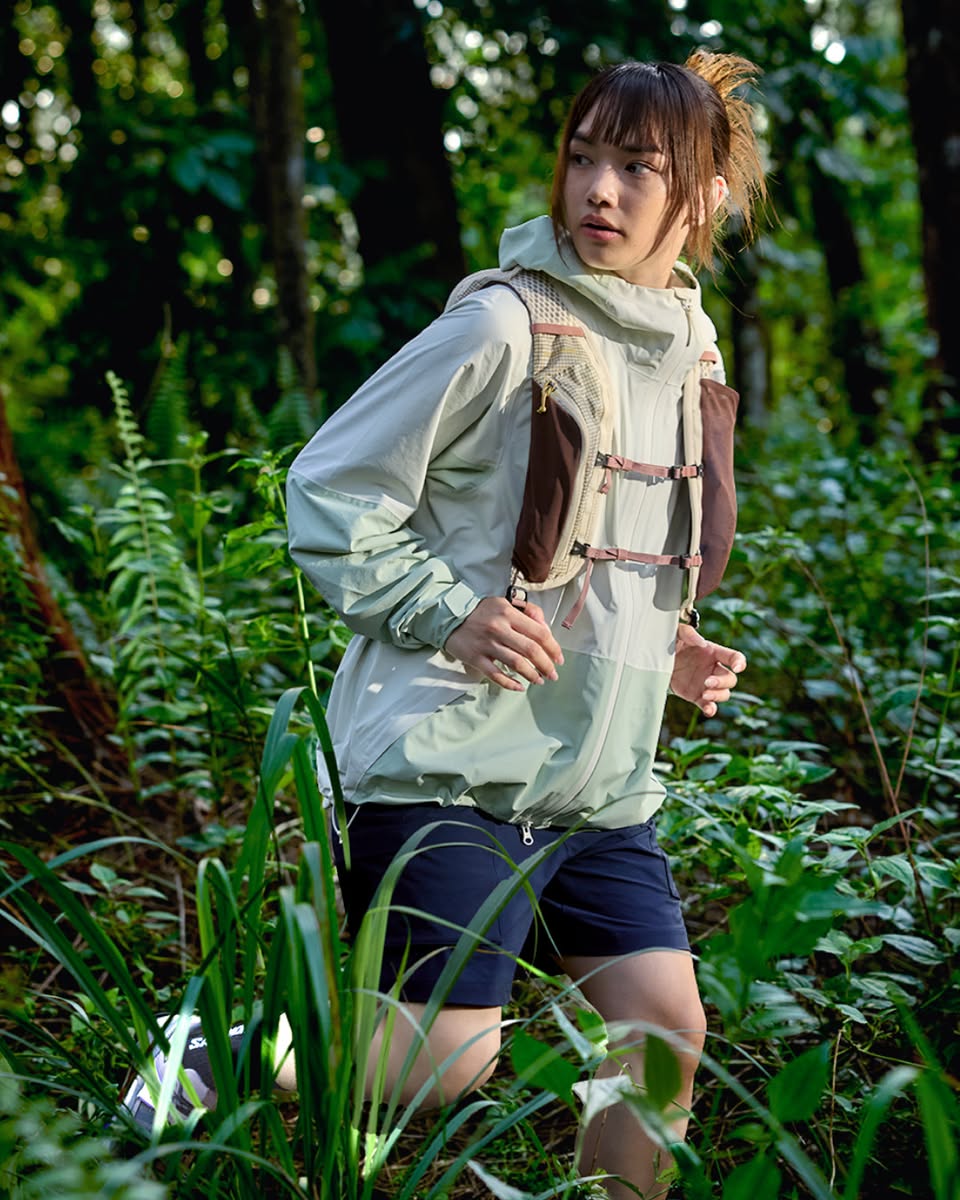 Hiker wearing outdoor jacket with mesh panels carrying backpack in forest