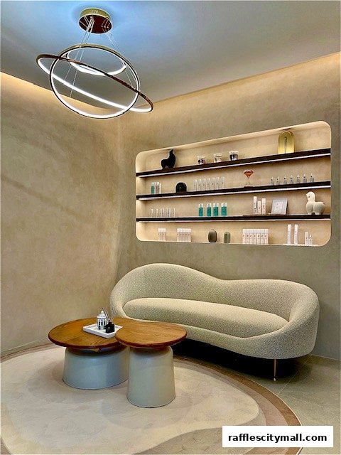 A stylish waiting area with a curved sofa, coffee tables, and shelves displaying beauty products.