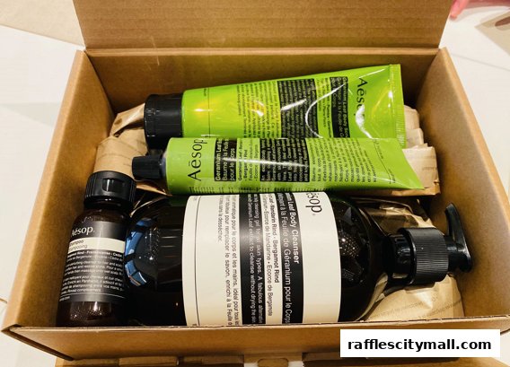 A cardboard box containing Aesop branded personal care products, including a body cleanser and two tubes.