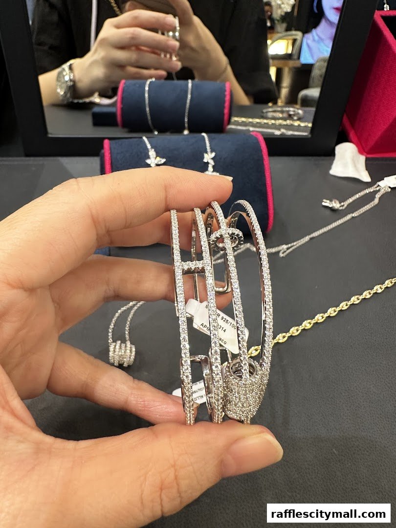 A hand holds a diamond-encrusted bracelet with price tags, showcasing APM Monaco jewelry.