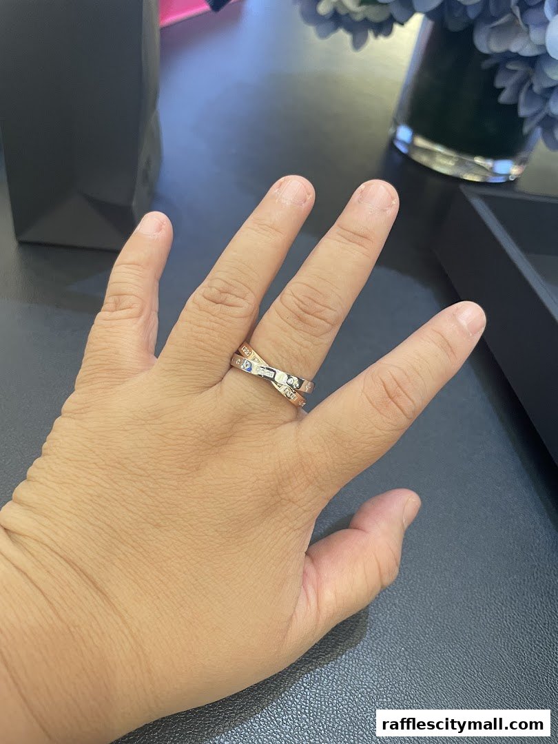 A hand wearing a stylish APM Monaco ring with a diamond-studded design.