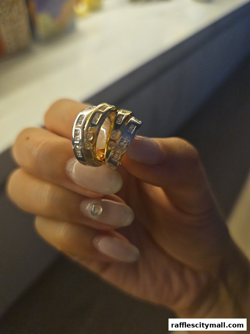 A hand with manicured nails holds two sparkling rings with diamond accents.