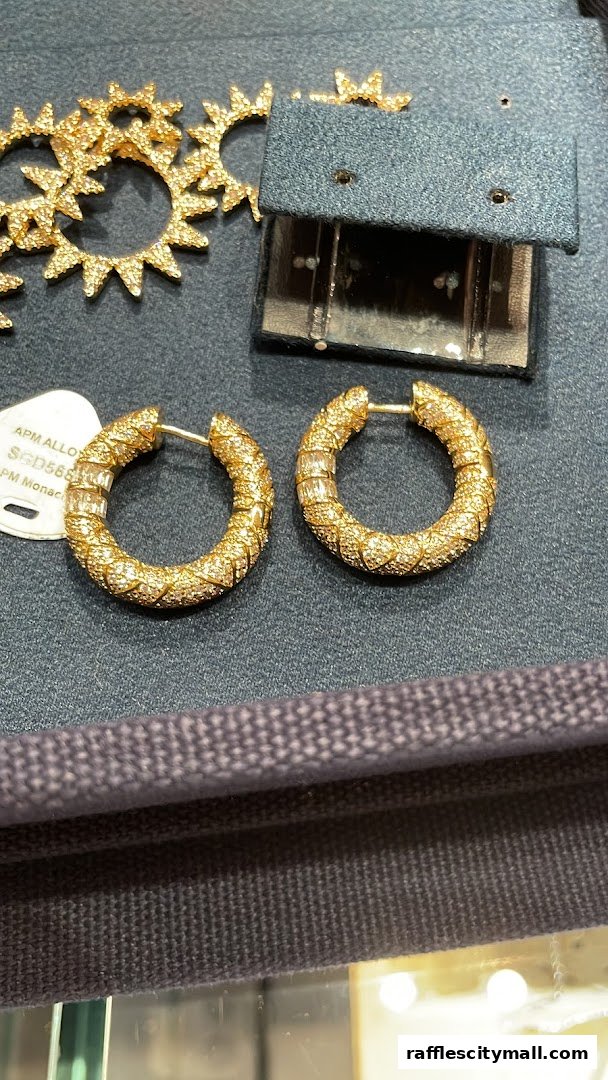 Close-up of sparkling gold hoop earrings with baguette-cut stones and sun-shaped earrings.