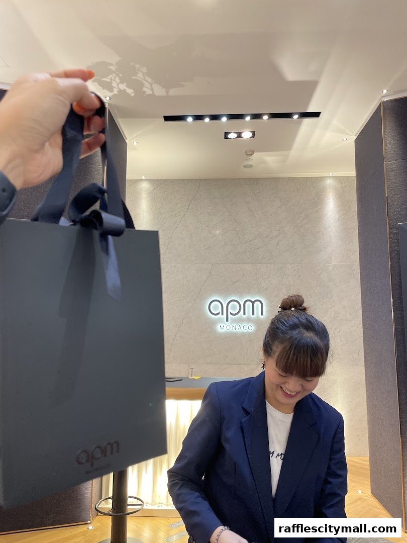 A person holds a shopping bag in front of the APM Monaco store with a smiling employee.