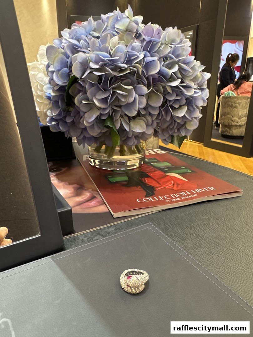 A close-up of a ring with a snake design and gemstones on a desk with flowers.