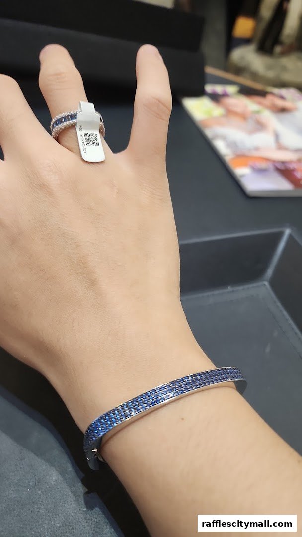 A hand wearing a sparkling blue gemstone ring and bracelet from APM Monaco.