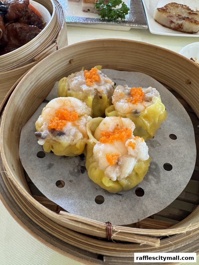 A close-up of steamed dumplings topped with shrimp and roe in a bamboo steamer.