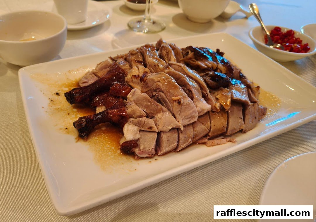 A platter of sliced roasted duck with crispy skin and tender meat, served with a side of chili.