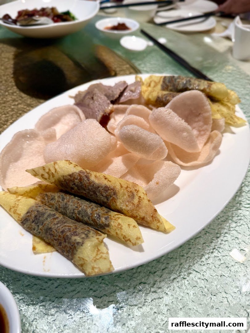 A plate of Asian appetizers, including crispy crackers and spring rolls, served at a restaurant.