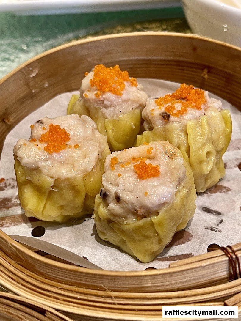 A close-up shot of four delicious dim sum dumplings topped with orange roe in a bamboo steamer.