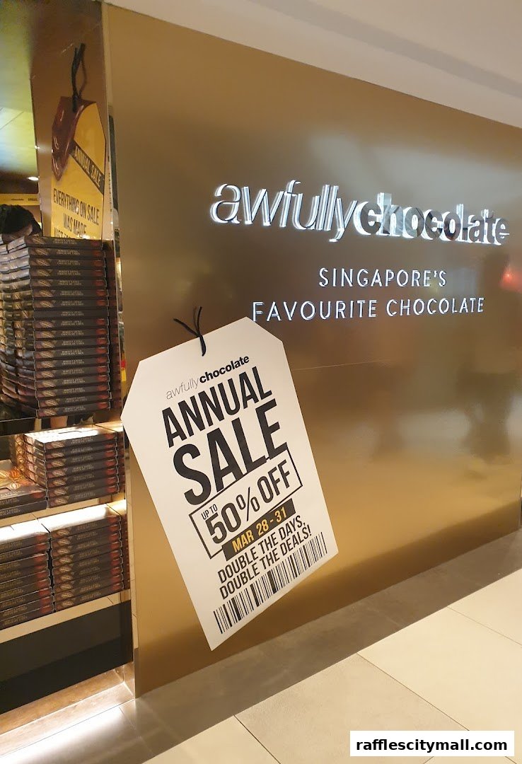 Awfully Chocolate shop front with an annual sale sign offering up to 50% off.