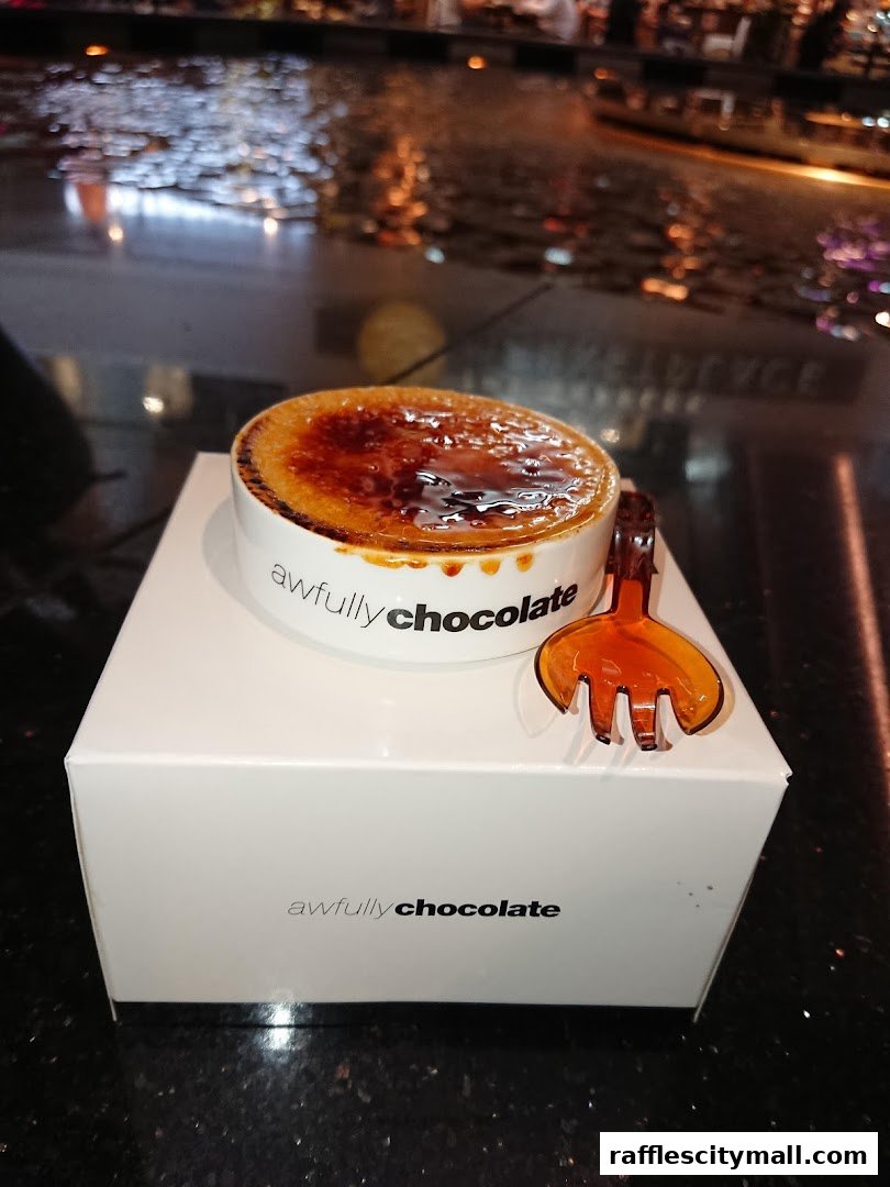 A crème brûlée dessert in a white bowl with a fork on an Awfully Chocolate box.