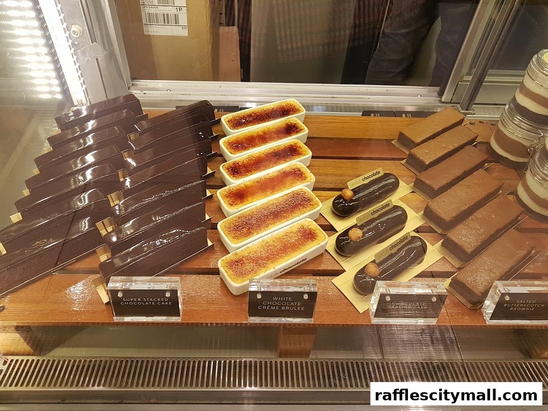A display case filled with various chocolate desserts, including cakes, eclairs, and creme brulees.