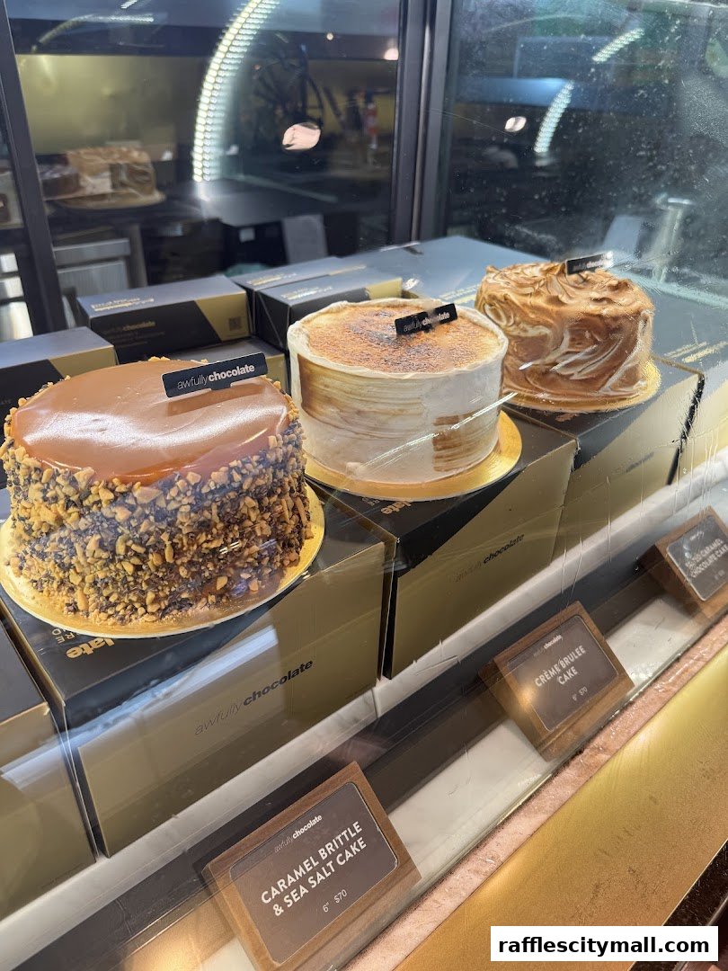 A display of three beautifully decorated cakes in a shop window.