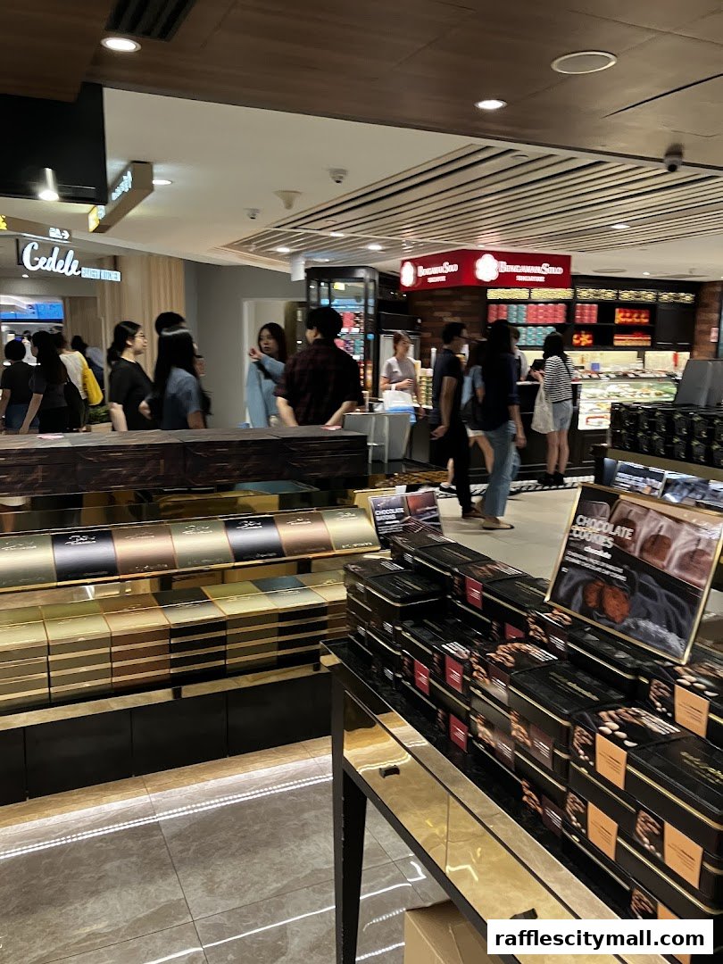 A busy chocolate shop with customers browsing displays of chocolates and cookies.
