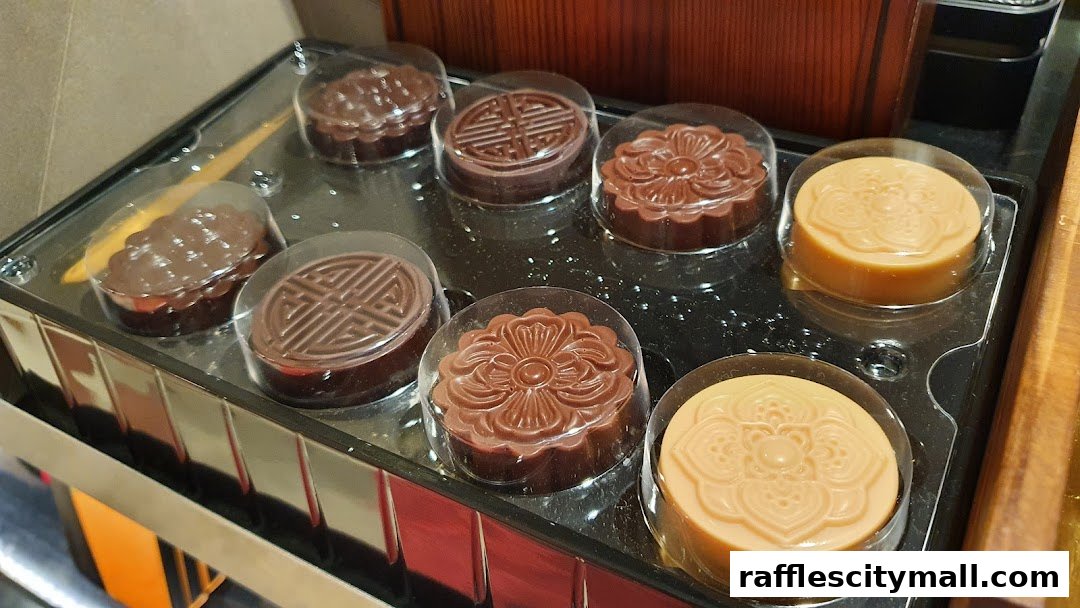 A tray of assorted chocolate and caramel mooncakes with intricate designs.