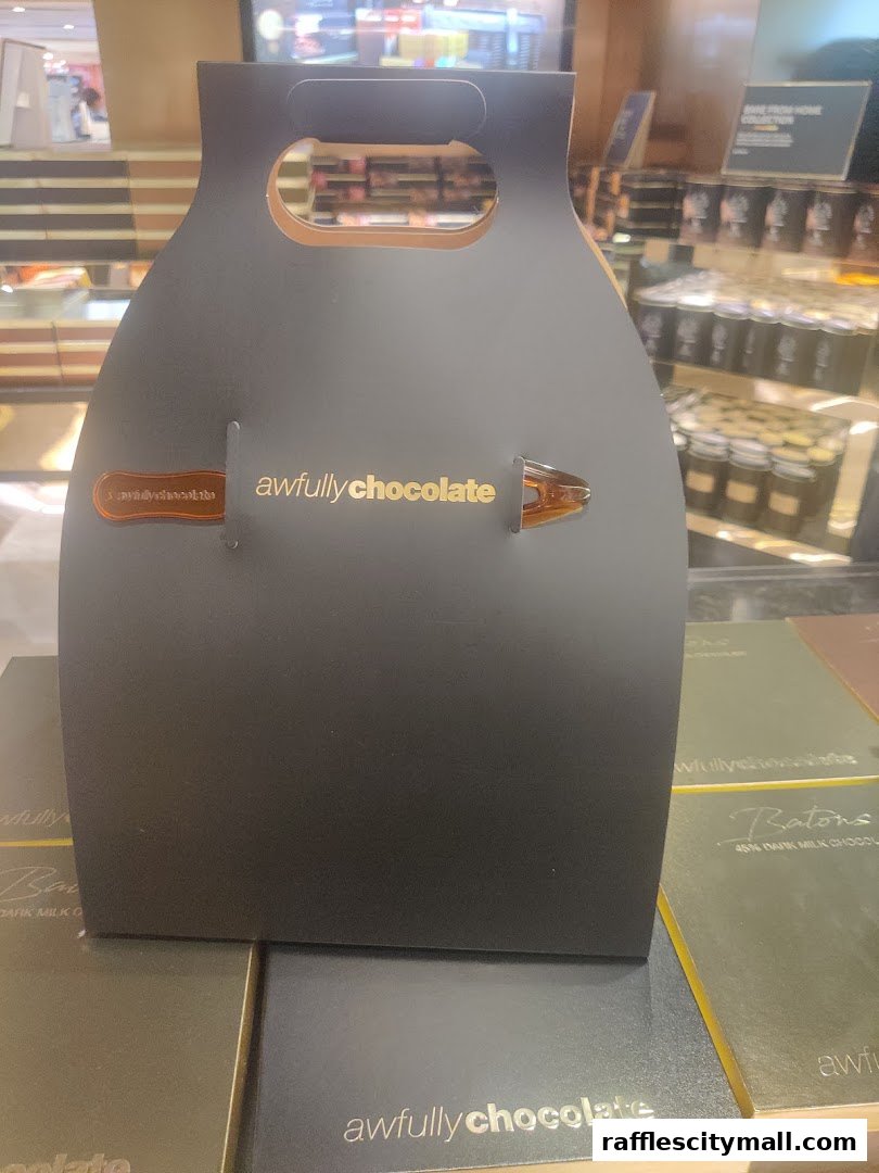A black gift bag with 'awfullychocolate' branding and a chocolate bar inside.
