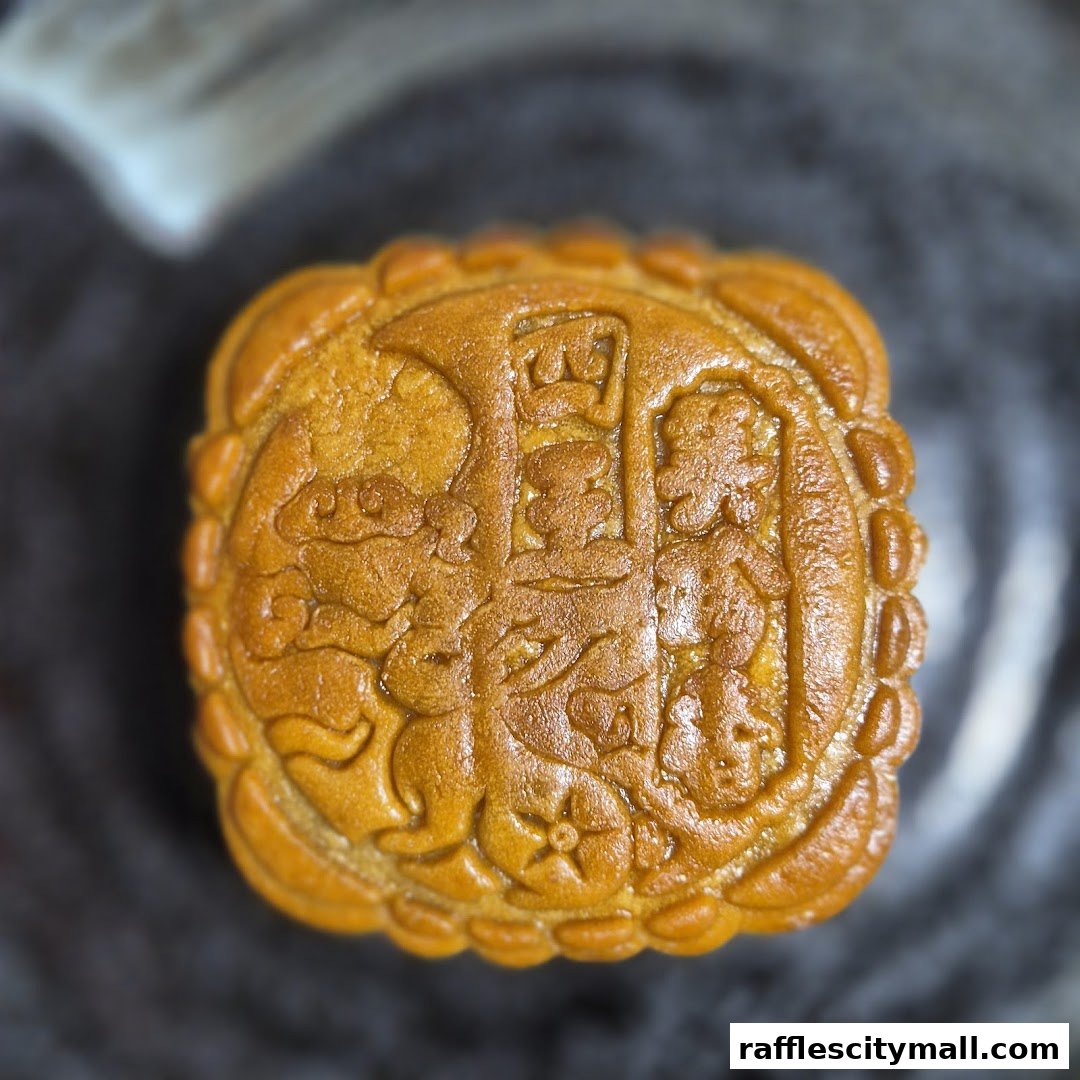 A close-up shot of a golden-brown mooncake with intricate traditional Chinese carvings.