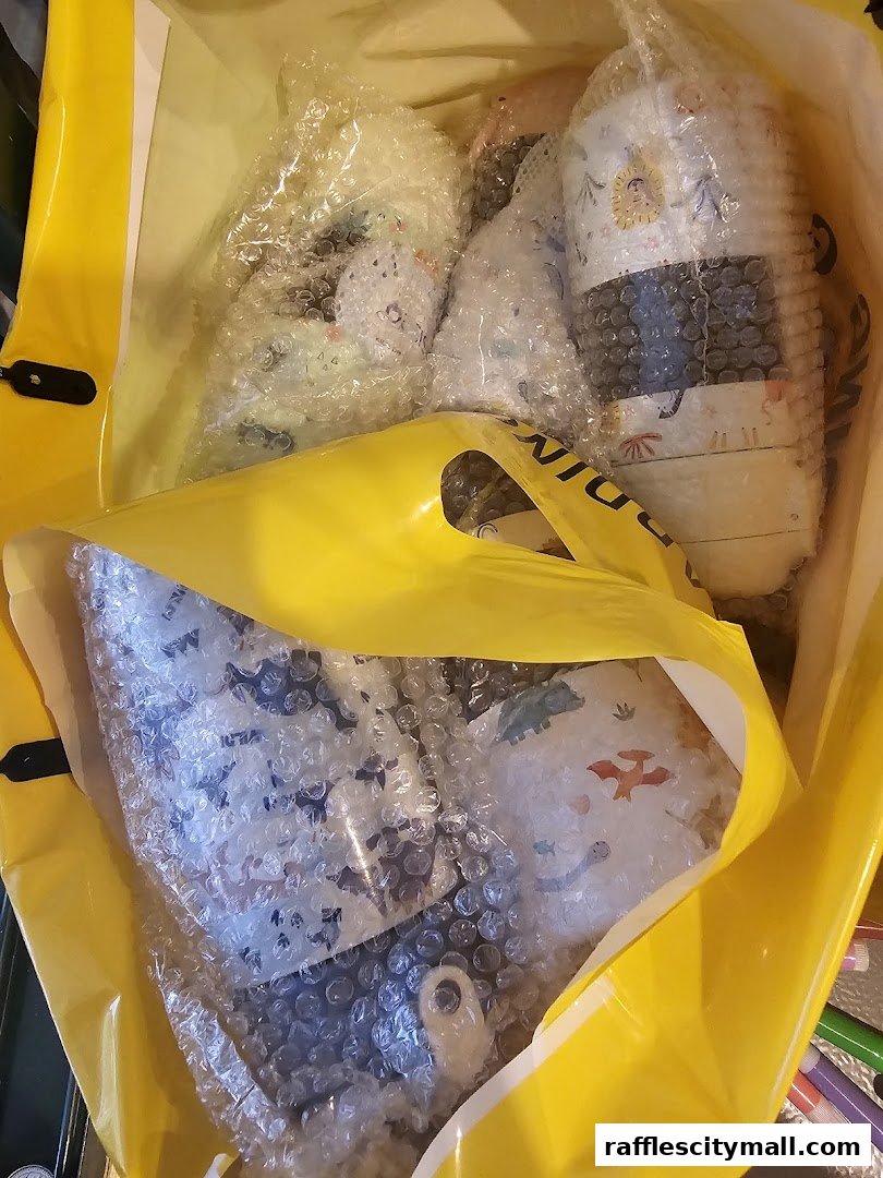 A bright yellow shopping bag filled with bubble-wrapped items featuring playful dinosaur and celestial prints.