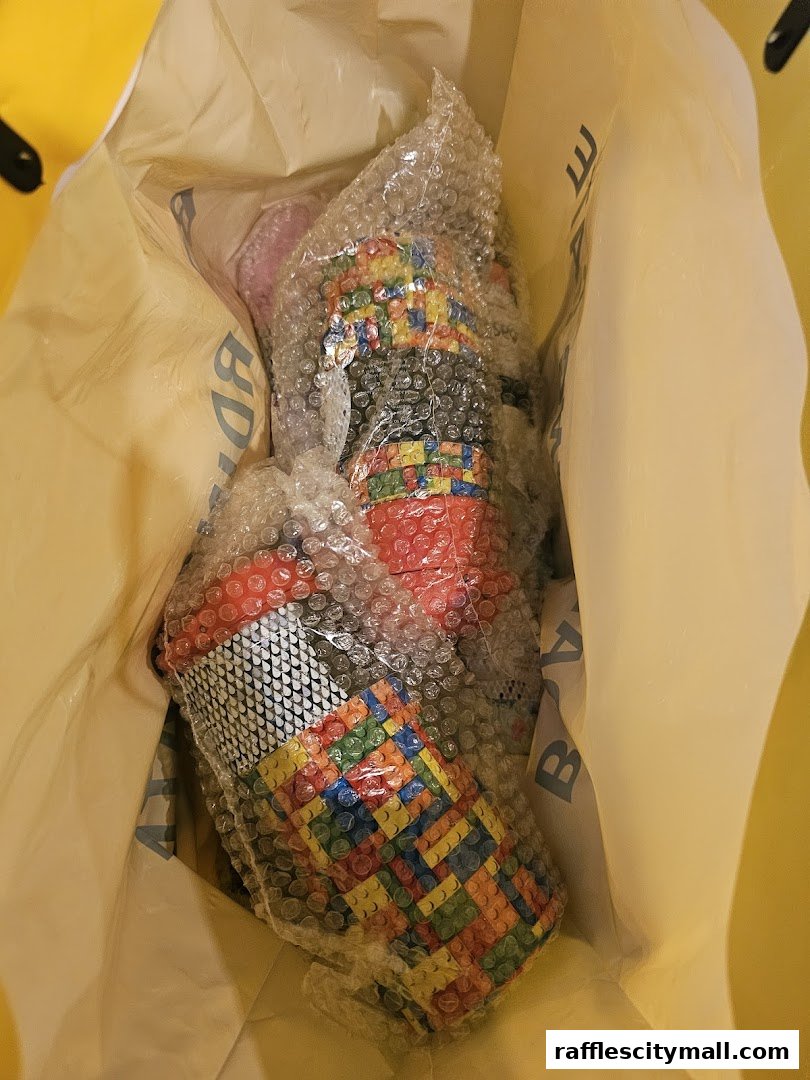 A yellow shopping bag containing bubble-wrapped items with colorful, block-like patterns.