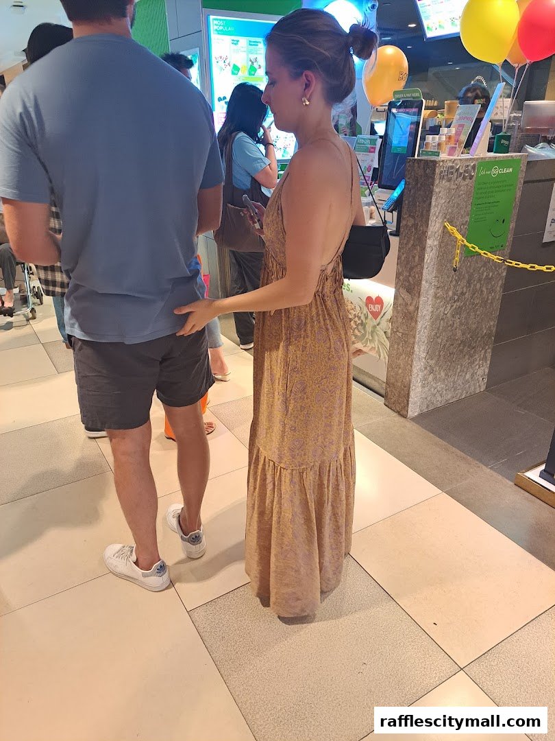 People queuing at a Boost Juice counter with colorful balloons and menu displays.