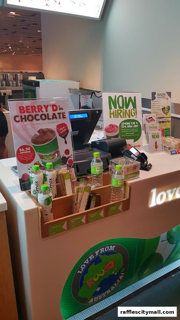 A Boost Juice counter displaying a chocolate smoothie promotion and hiring advertisement.