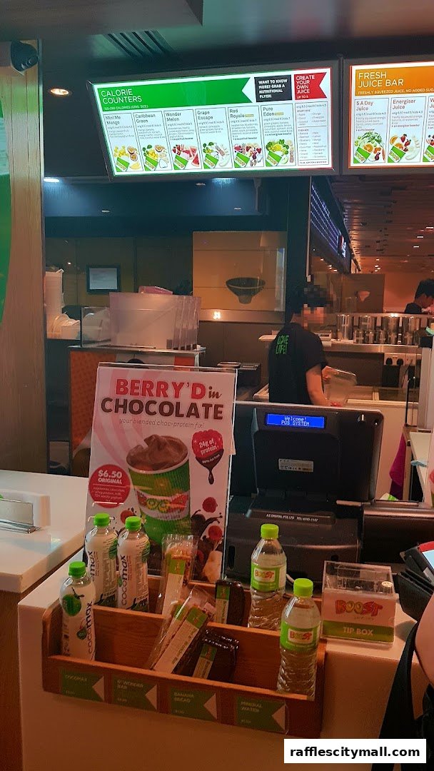 Boost Juice counter with a featured 'Berry'd in Chocolate' drink and various bottled beverages.
