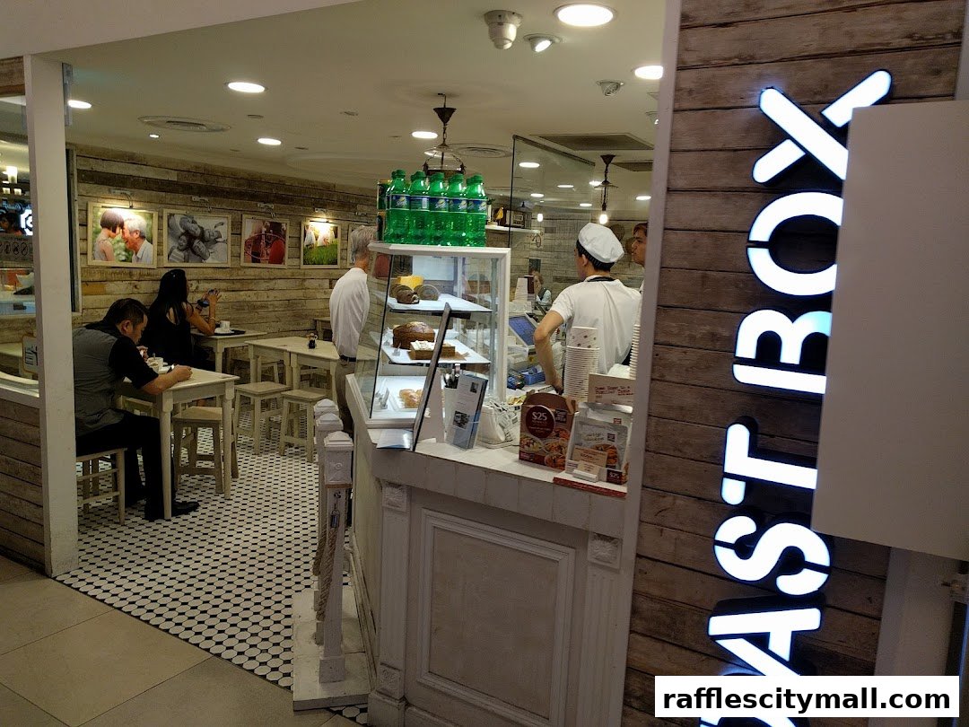 Interior of a bakery with customers and staff, featuring display cases with baked goods.