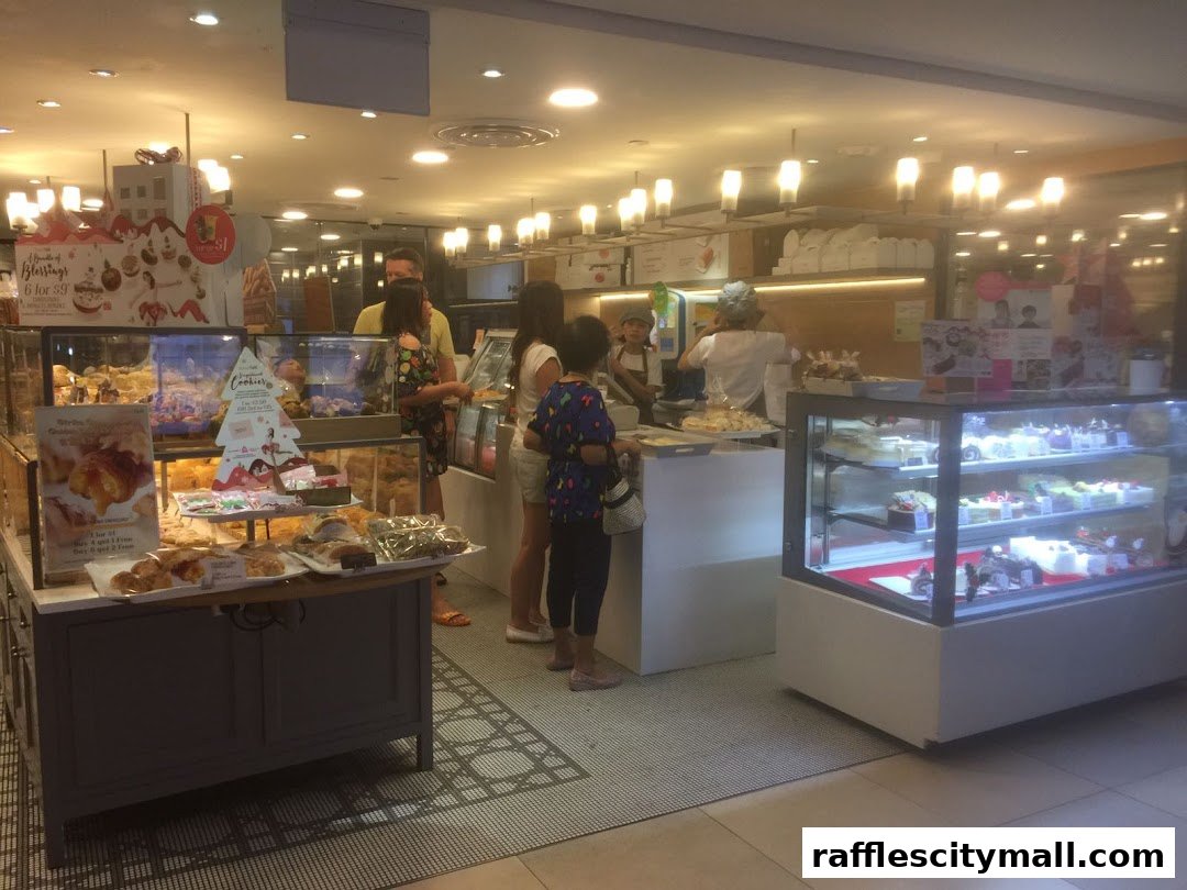 Customers browse a bakery display filled with pastries and cakes, with staff serving behind the counter.