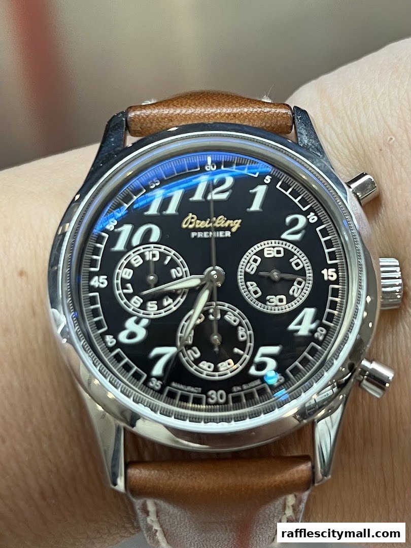A close-up shot of a Breitling Premier watch with a black dial and brown leather strap.