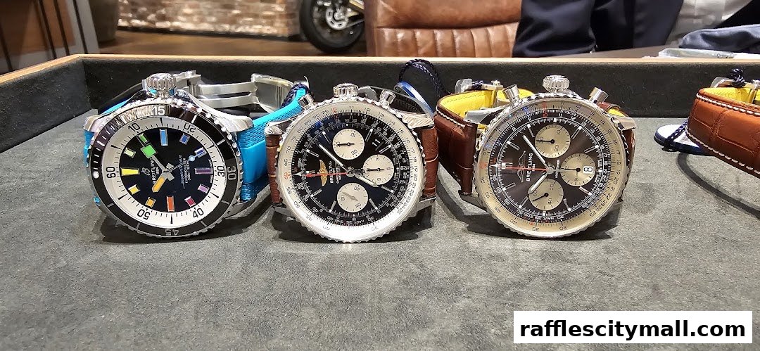 Three Breitling watches with different dial designs and straps displayed on a textured surface.