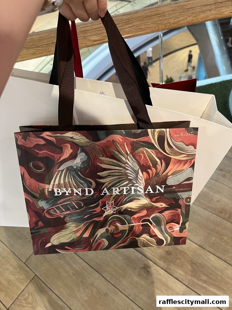 A person holds shopping bags from Bynd Artisan, featuring a colorful artistic design.