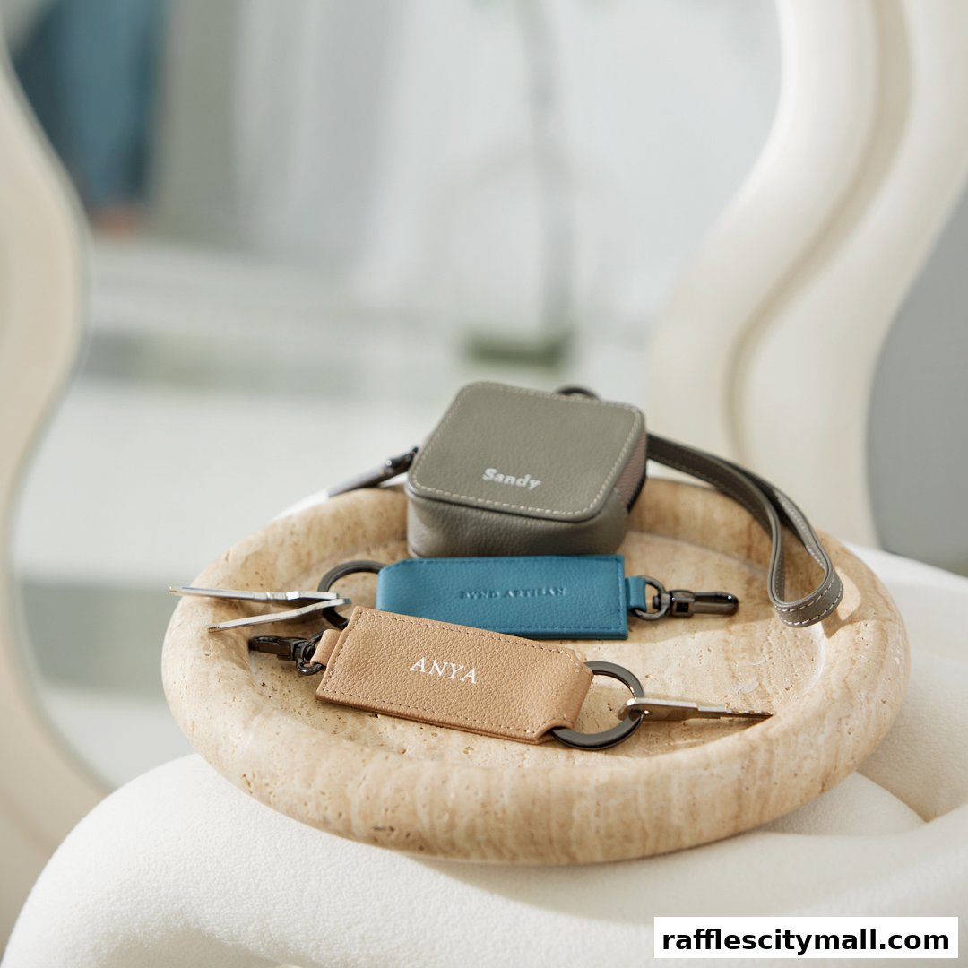 Personalized leather accessories including a small pouch and keychains on a textured tray.