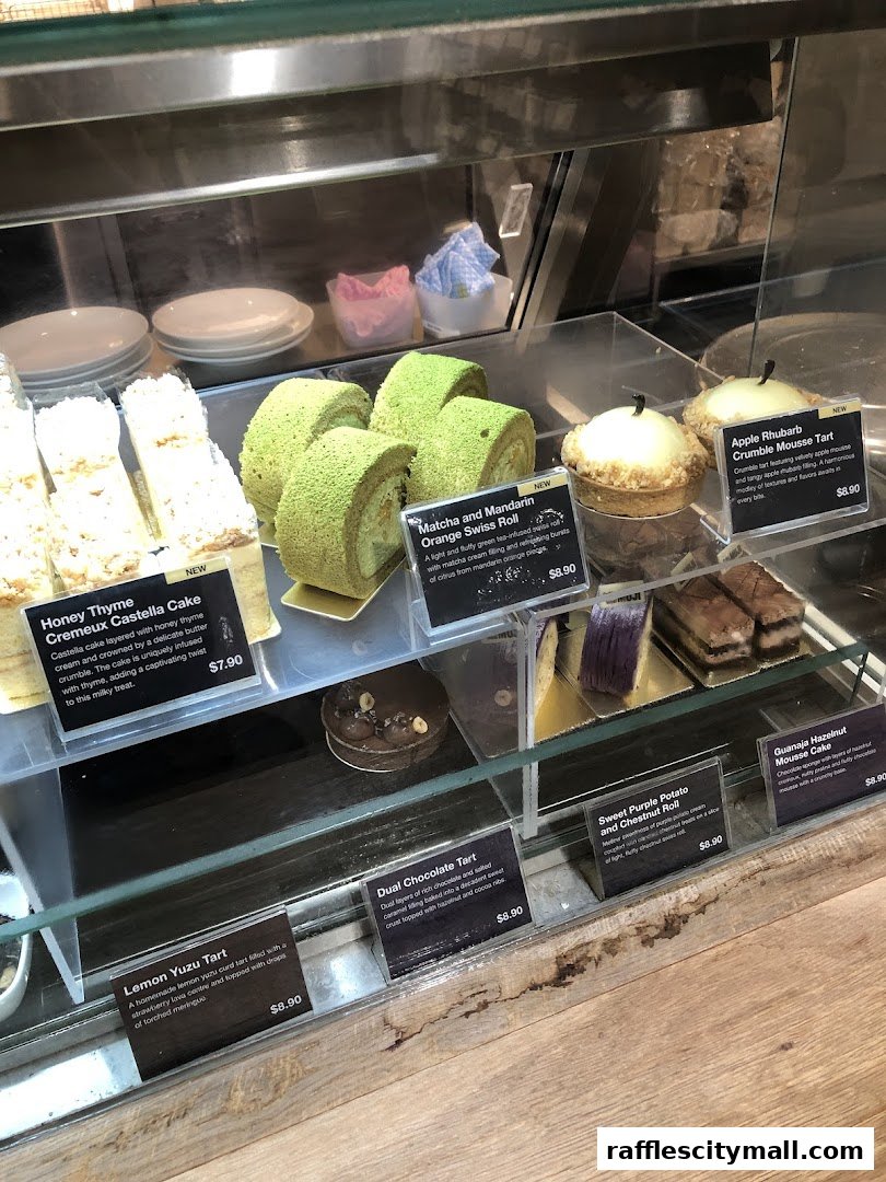 A display case filled with various cakes and pastries, including Swiss rolls and tarts.