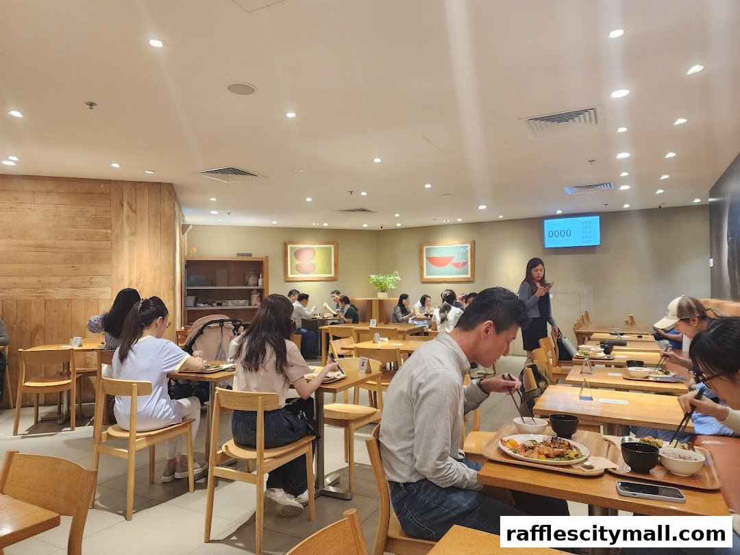 Diners enjoy meals at tables inside a brightly lit cafe with wooden accents.