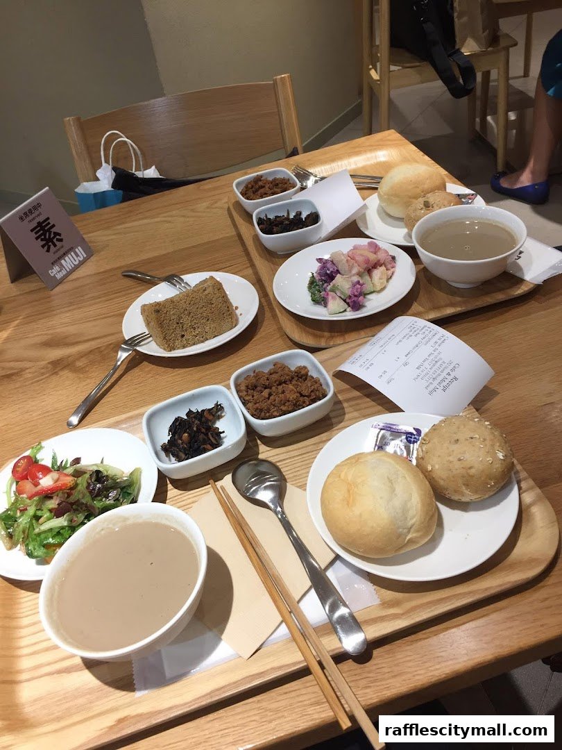 A table laden with various dishes, including salads, bread, and bowls of food, at CafeMeal MUJI Raffles City.