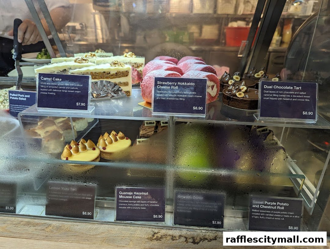 A display case filled with various cakes and pastries, including carrot cake, strawberry roll, and tarts.