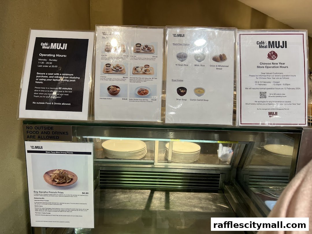 A display of menus and operating hours for CafeMeal MUJI Raffles City.