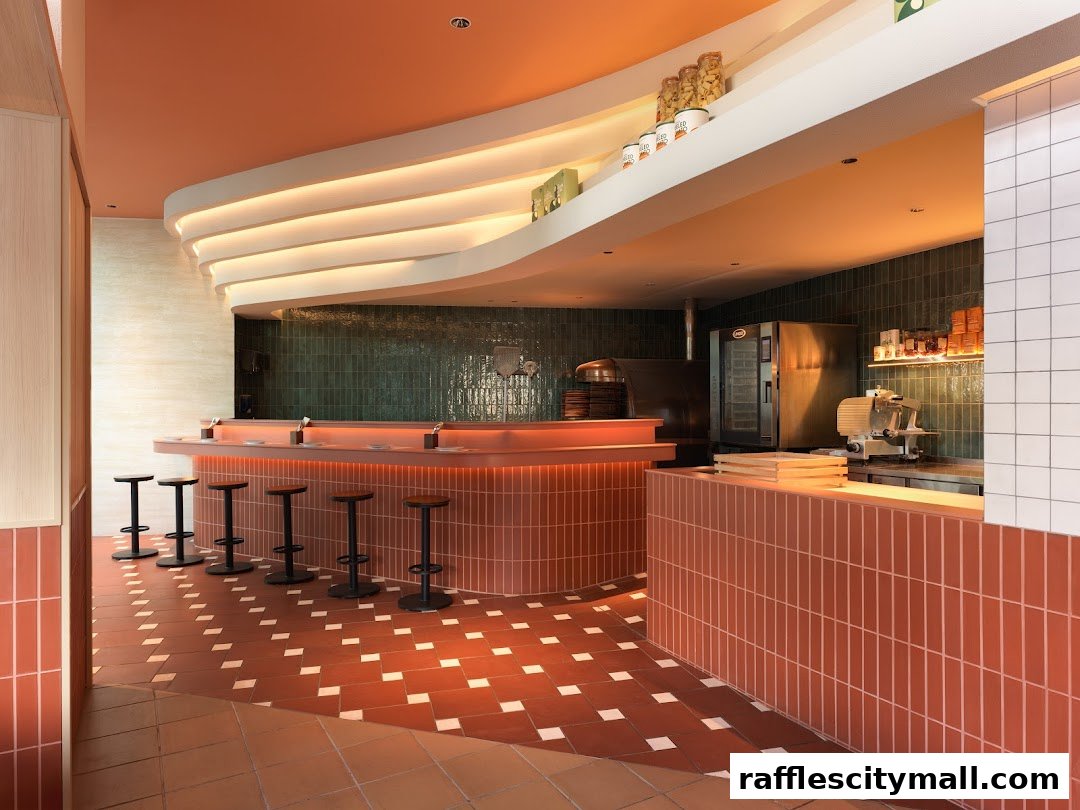 Interior of a modern restaurant with a curved bar, stools, and kitchen equipment.