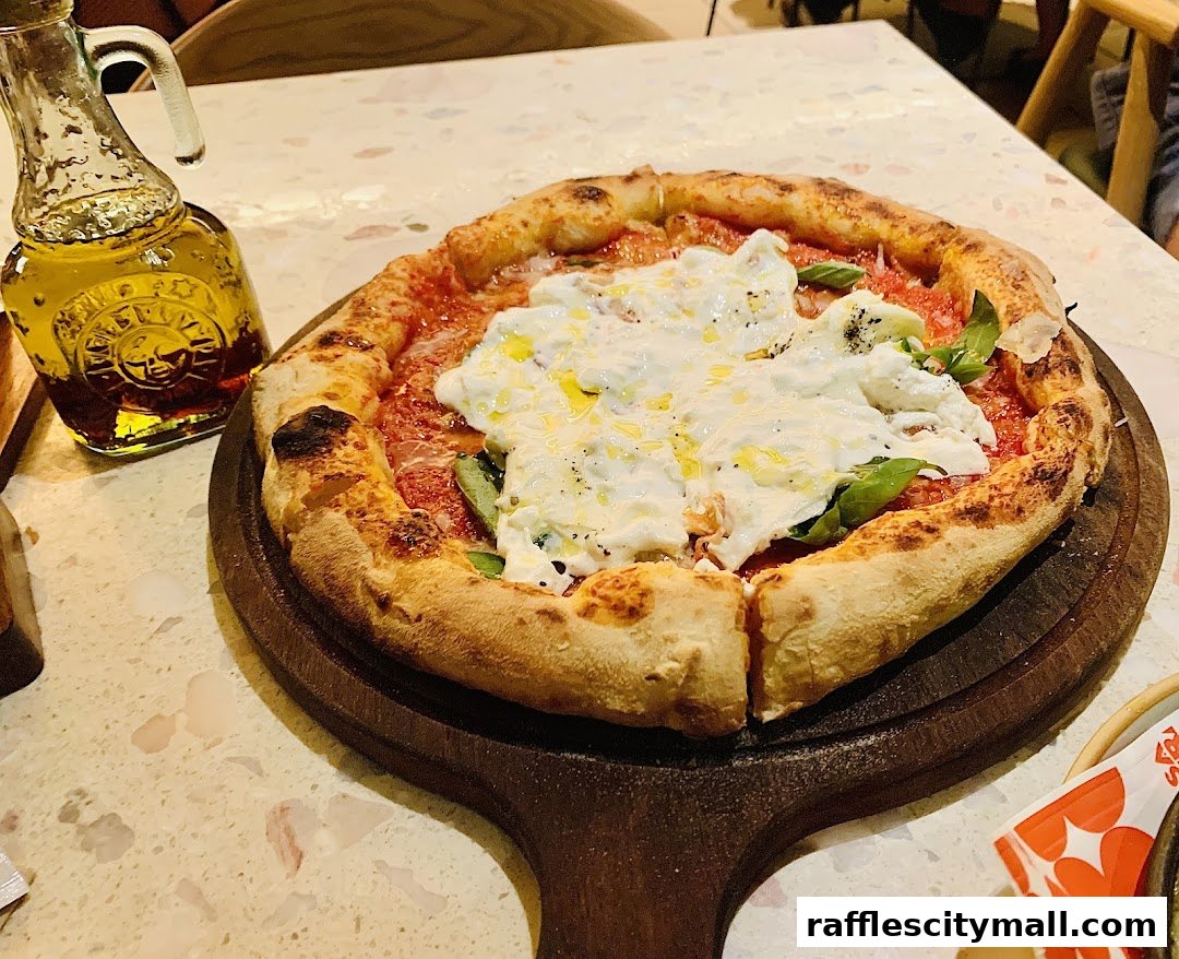 A delicious pizza with creamy cheese and basil, served with a bottle of olive oil.