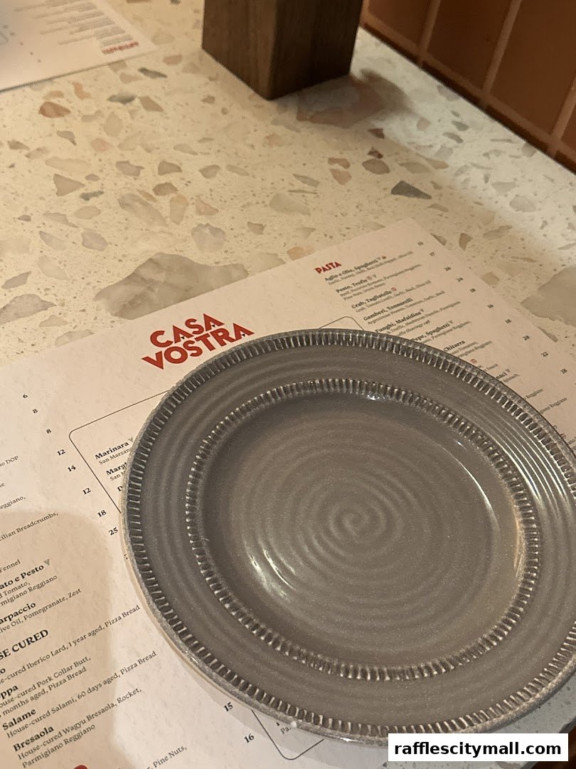 A close-up of a menu from Casa Vostra with a plate on top.