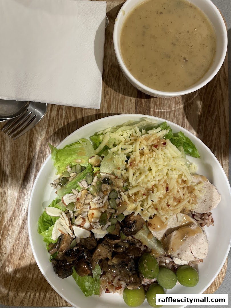 A healthy and delicious salad with chicken, mushrooms, nuts, seeds, and olives, served with a side of soup.