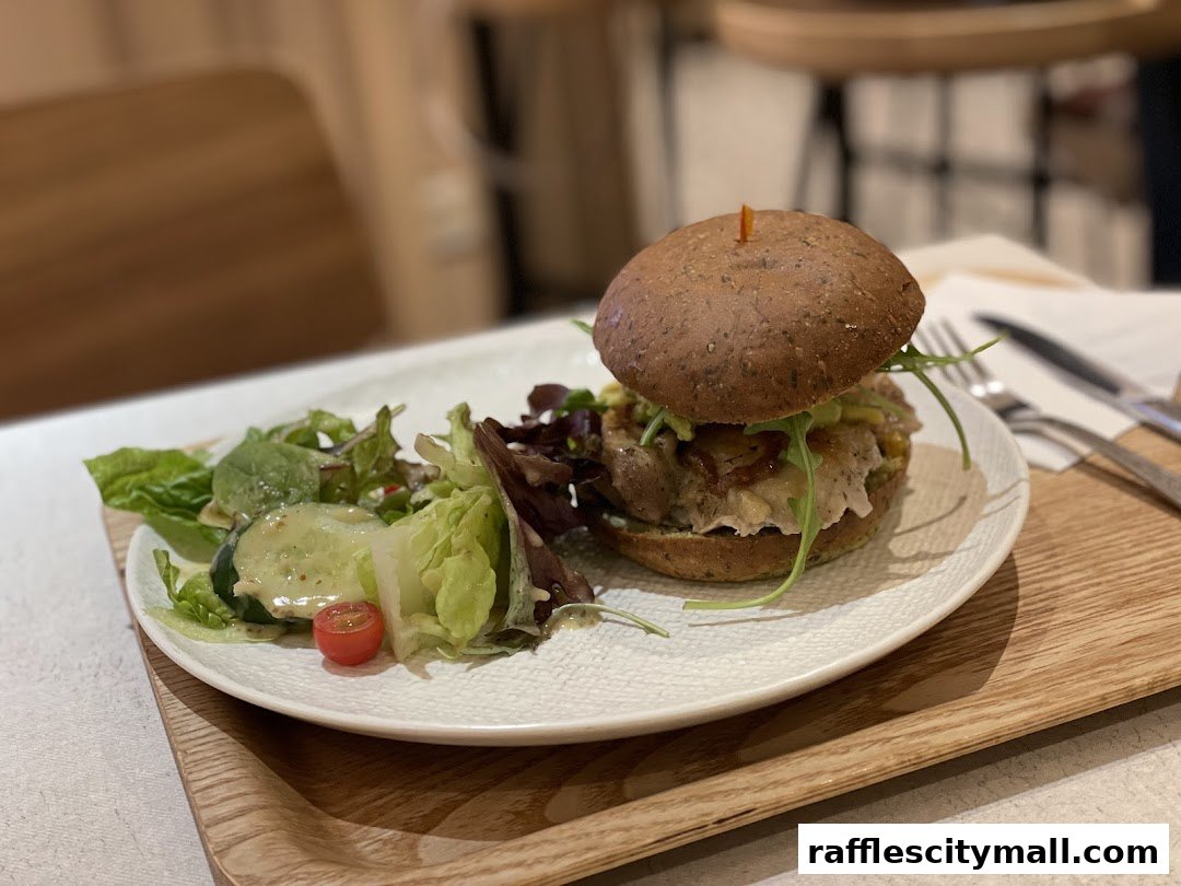 A delicious burger and salad served on a white plate with a wooden tray.