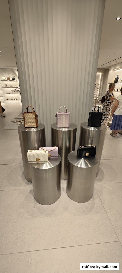 A display of stylish handbags on cylindrical pedestals inside a modern retail store.