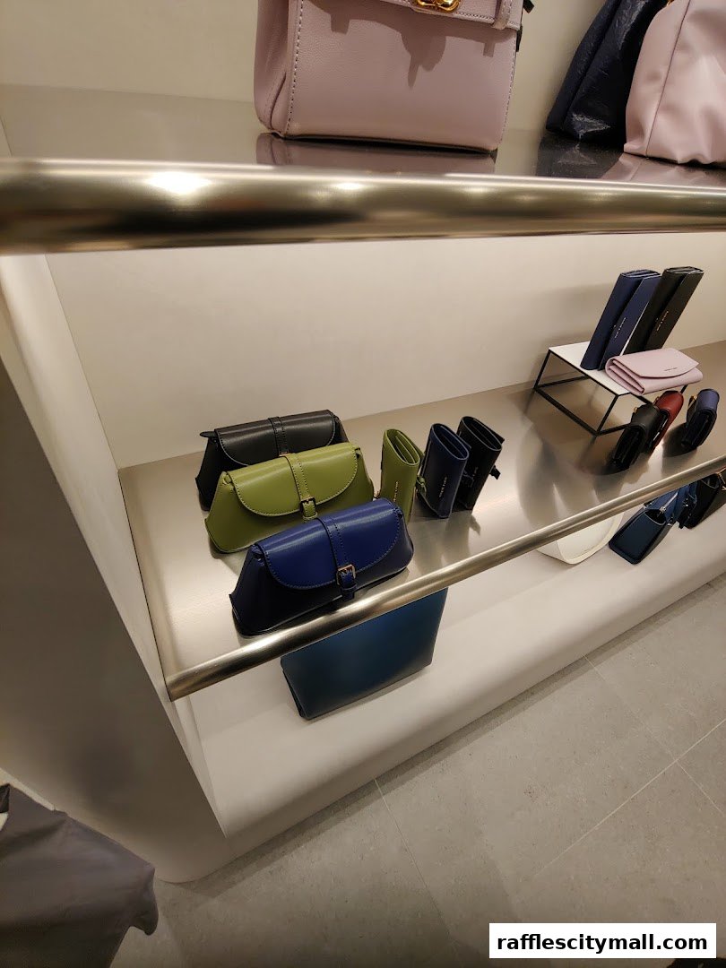 A display of stylish Charles & Keith handbags and wallets in various colors on shelves.