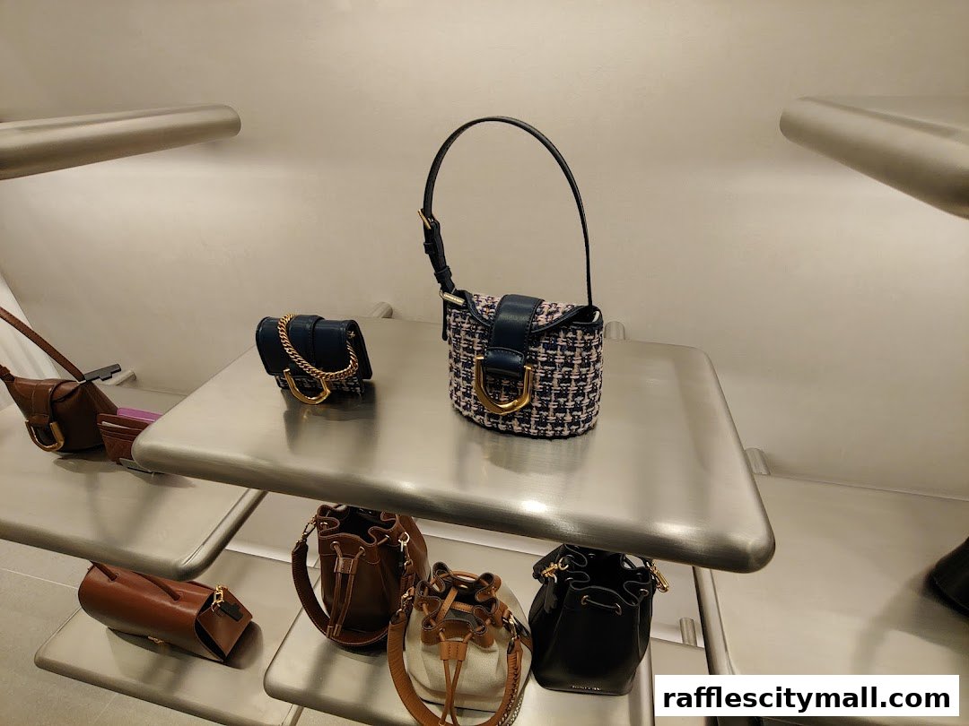 A display of various stylish handbags from Charles & Keith on sleek shelves.