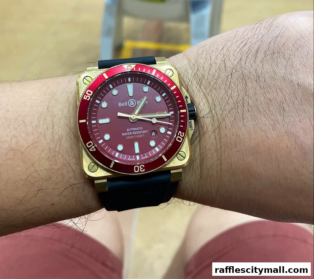 A close-up shot of a person wearing a gold and red Bell & Ross automatic watch.