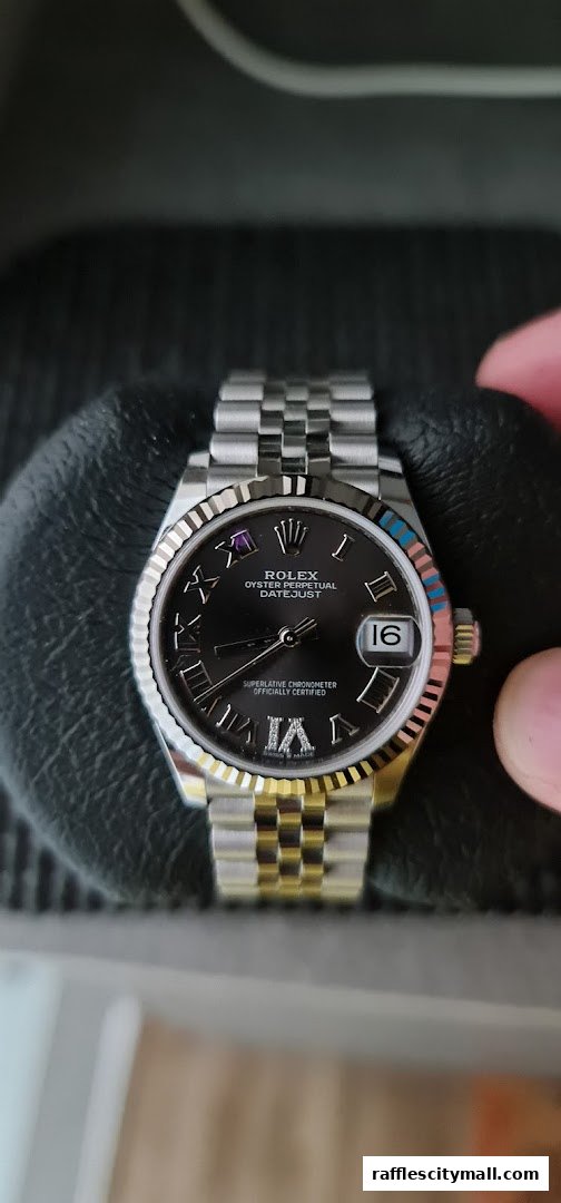 A close-up of a Rolex Datejust watch with a black dial and a two-tone Jubilee bracelet.