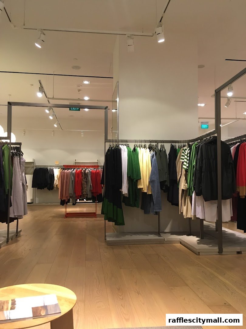 Interior view of a COS clothing store with racks of apparel and a coffee table.
