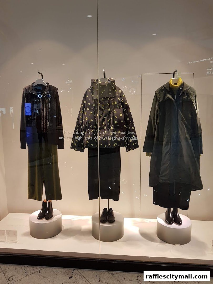 A COS shop window display featuring three mannequins dressed in stylish winter clothing.